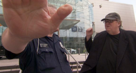 Documentary filmmaker Michael Moore butts heads with security guards while trying to get into GM's corporate offices.